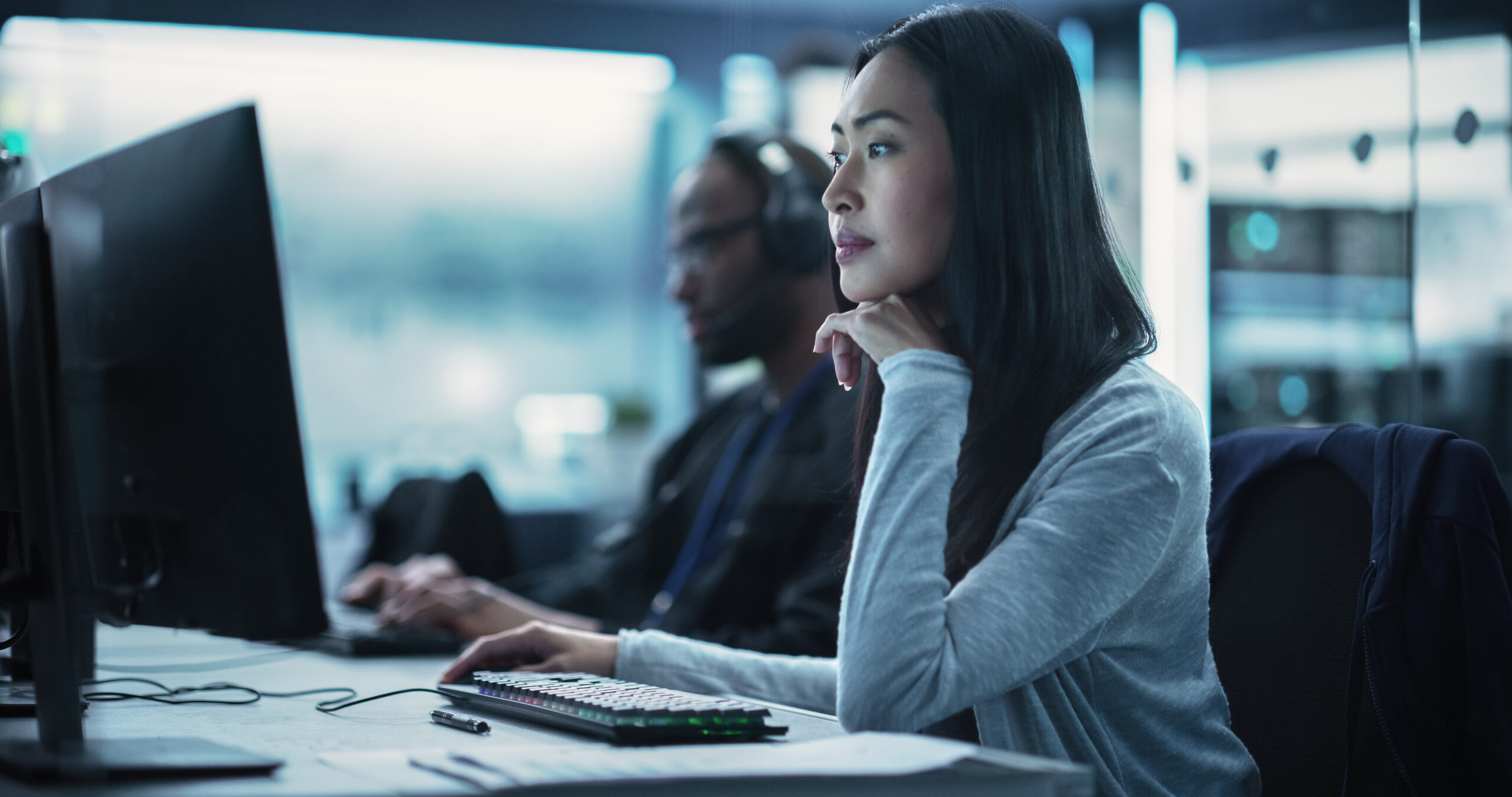 Beautiful Young Asian Female Specialist Working on Computer Together with Professional Colleagues. Data Protection Center with Server Facility, Storage Hardware and Corporate Science Atmosphere