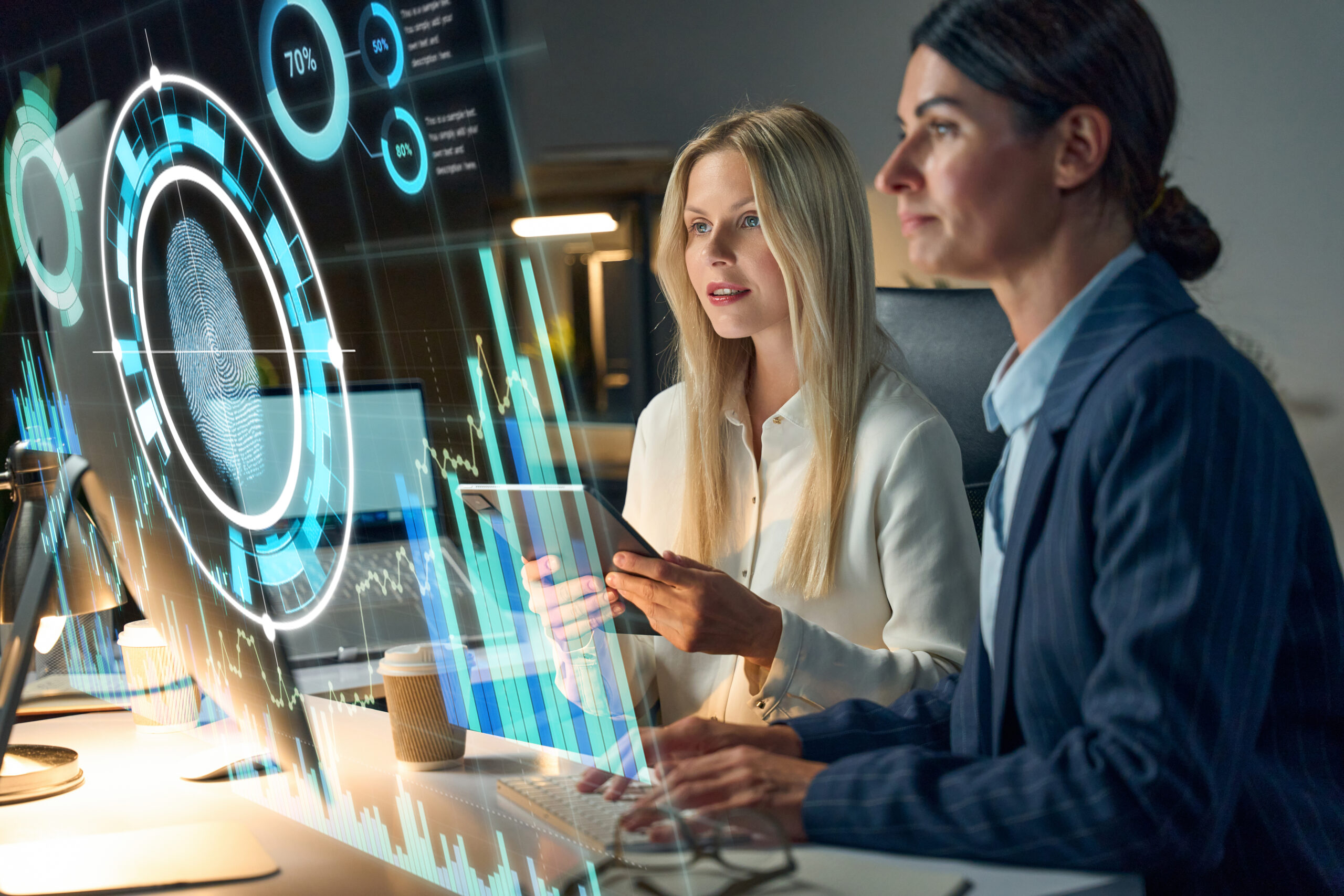 Two Businesswomen Analyzing Cybersecurity Data Visualizations on Screens in Modern Office